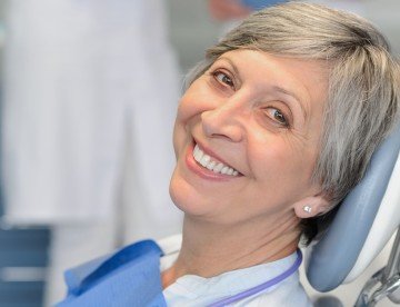 Senior woman patient with dentist team at dental surgery smiling